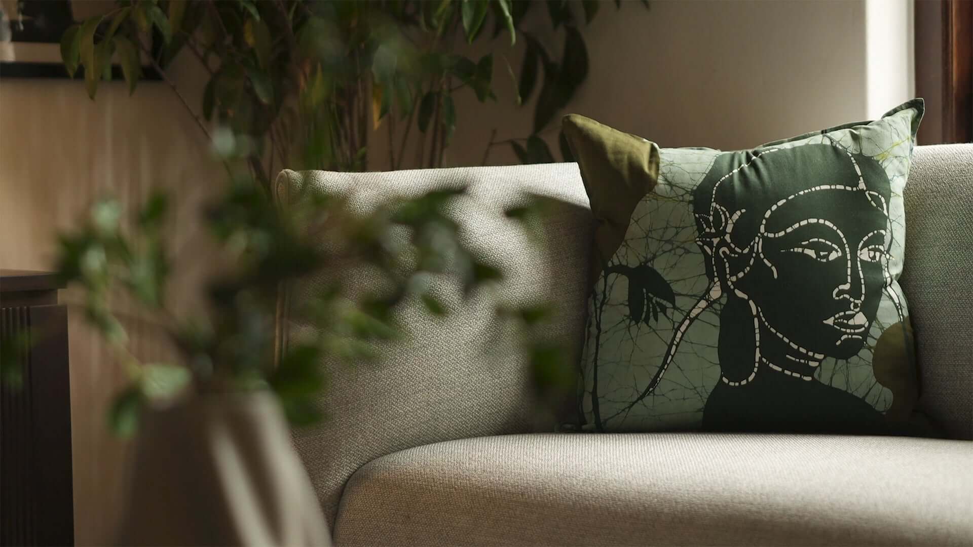 Apsara handmade cotton batik throw pillow in forest green on sage green, 18" x 18" on sofa, by Kohomba Life – close-up view.