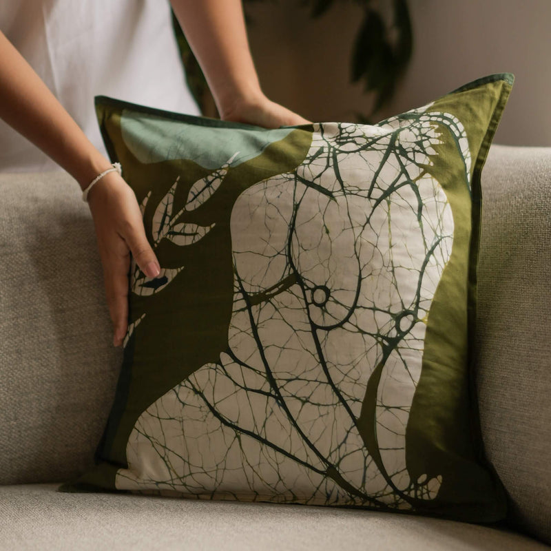 Placing Lalana handmade cotton batik throw pillow in forest ivory on forest green, 18" x 18", by Kohomba Life on sofa – close-up.