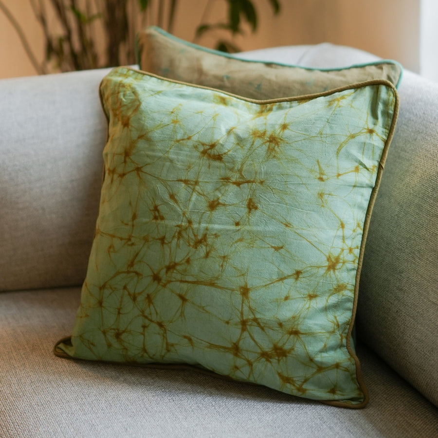 Thaalam handmade cotton batik throw pillow in khaki green on sage green, 18" x 18", by Kohomba Life with another behind.