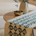 Thrigona handmade cotton batik table and bed runner in teal blue on rye, 90" x 14", from Kohomba Life – 
 styled on a dining table.